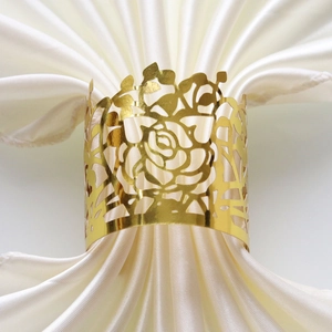 Close-up of golden hollow rose napkin ring with intricate floral leaf pattern