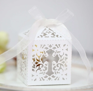 Detail of white laser-cut gift box with hollow floral patterns and cross ribbon bow