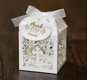 Macro detail of laser-cut white wedding gift box with cross pattern and thank you tag