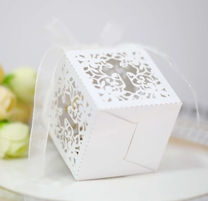 Macro shot of white laser-cut cross floral candy box with elegant silk ribbon detail