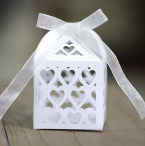 Close-up of laser cut hollow heart pattern on white wedding favor box with ribbon bow