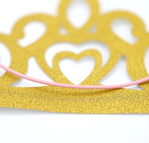 Detail view of gold glitter party crown with hollow heart design and pink elastic strap