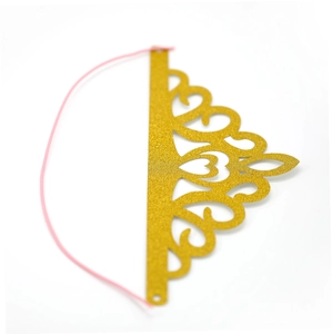 Detail of a golden glitter party crown with hollow patterns and pink elastic string