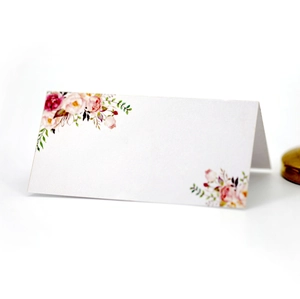 Close-up of white folding place card with elegant pink rose floral print for weddings