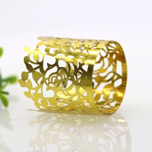 Macro detail of laser-cut gold paper napkin ring with elegant hollow rose flower pattern