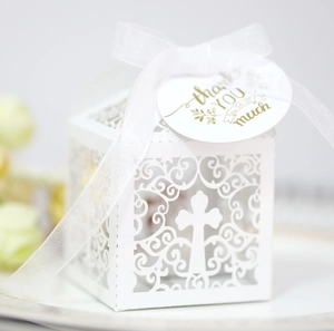 Detailed laser-cut hollow white wedding favor box with cross pattern and silk ribbon