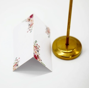 Close-up of white place card with pink floral pattern for weddings and banquets