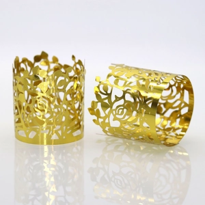 Close-up of golden hollow metal napkin ring with laser-cut rose floral pattern