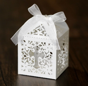 White laser-cut cross gift box with intricate floral patterns and organza ribbon