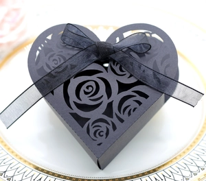 Close-up of black heart-shaped gift box with laser-cut rose patterns and silk ribbon