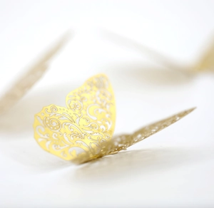 Macro detail of gold hollow-out 3D butterflies with intricate laser-cut floral patterns