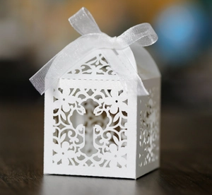 Detail of laser-cut cross and floral motifs on white pearlescent paper favor box