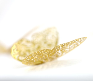 Macro shot of 3D laser-cut golden butterfly wall sticker with intricate hollow patterns