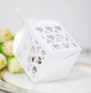 Close-up of white laser-cut heart favor box with silk ribbon for wedding candy