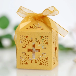 Dettaglio della scatola regalo gialla tagliata al laser con motivo a croce e fiocco in chiffon