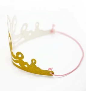Macro shot of glittery gold laser-cut birthday crown with pink elastic headband detail