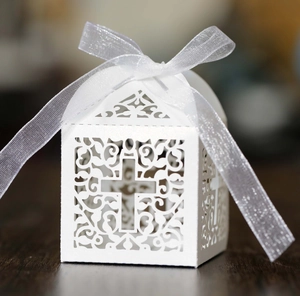 Detail of laser-cut white favor box with cross motif and elegant organza ribbon tie