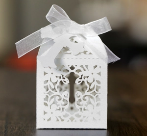 Detailed laser-cut hollow cross patterns on white wedding candy box with ribbon