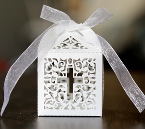 Detail of laser-cut cross and vine patterns on a white pearlescent paper favor box