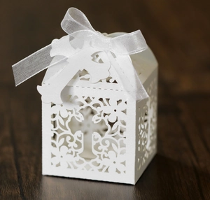 Close-up of laser cut hollow cross patterns on white wedding favor gift box with ribbon