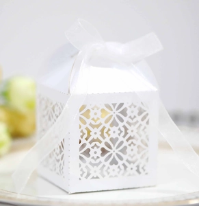 Elegant white laser-cut hollow candy box with floral patterns and a white silk ribbon bow