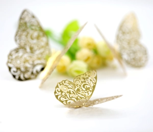 Macro detail of 3D hollow gold paper butterfly with intricate laser-cut floral patterns