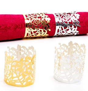 Close-up of golden and silver rose cutout napkin rings on a red cloth napkin