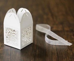 Detail of white laser-cut rose hollow favor box with translucent white mesh ribbon