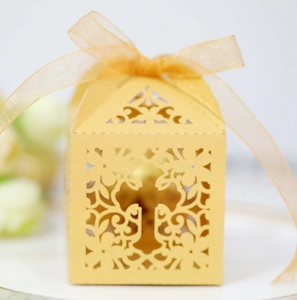 Detail of laser-cut cross floral pattern on golden candy box with ribbon bow