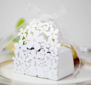 Detail of laser-cut flower patterns on white wedding candy box with ribbon