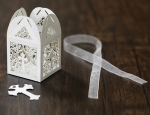 Detail of white laser-cut favor box with floral patterns and religious cross cutout