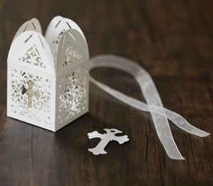 Detail of laser-cut white wedding candy box with floral patterns and a cross tag