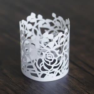 Detail of laser-cut rose and vine pattern on elegant white paper napkin rings