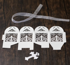 Detail of white laser-cut wedding favor box with cross pattern and silk ribbon ties