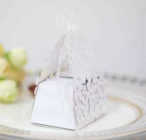 Detail of laser-cut flower patterns on white wedding candy box with silk bow