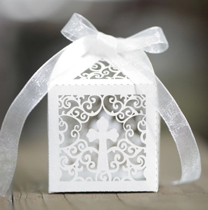Detail of laser-cut wedding favor box with white ribbon and intricate cross hollow pattern
