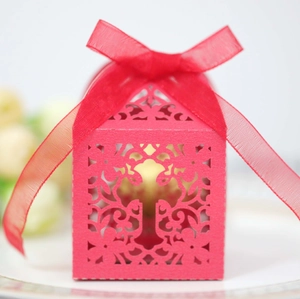 Close-up of laser-cut pink wedding favor box with cross pattern and chiffon ribbon