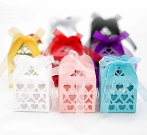 Close-up of laser-cut heart hollow favor boxes with organza ribbons in various colors