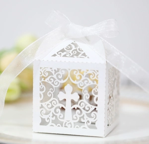Detail of laser-cut white hollow cross gift box with elegant ribbon for baptism ceremony