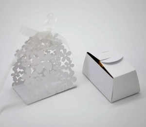 Detail view of hollow laser-cut floral candy box and white gift box with silk ribbon