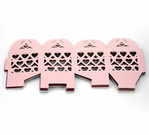 Flat lay of pink laser-cut candy box with heart patterns and colorful options below
