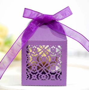 Detail of purple laser-cut wedding candy box with elegant floral pattern and silk ribbon