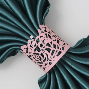 Macro shot of pink laser-cut paper napkin ring with elegant floral rose pattern