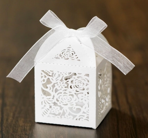 Close-up of white laser-cut rose favor box with an elegant organza ribbon bow