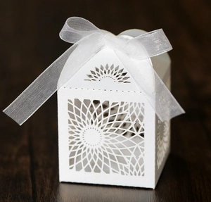 Macro detail of laser-cut white favor box with sunflower pattern and silk ribbon