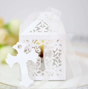 Detail of laser-cut white hollow wedding favor box with ribbon and cross tag