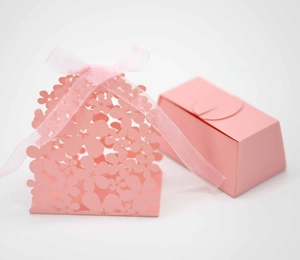 Close-up of pink hollow flower candy box with satin ribbon for wedding gift packaging