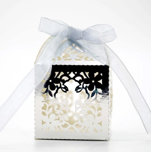 Close-up of silver laser-cut cross wedding favor box with elegant light blue ribbon bow