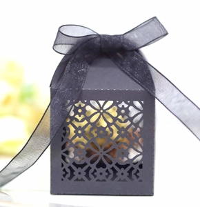 Detail showing laser-cut floral pattern on black favor box with sheer ribbon bow