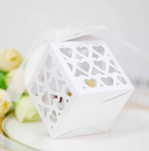 Detail of laser-cut heart pattern on white diamond-shaped wedding favor candy box
